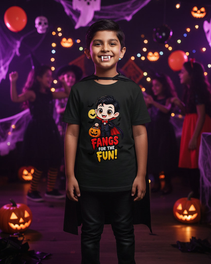 A black short-sleeve crewneck t-shirt with a cartoon vampire graphic on the chest. The graphic features a cute vampire character holding a jack-o'-lantern next to a yellow moon, with the text 'FANGS FOR THE FUN!' in red and yellow.